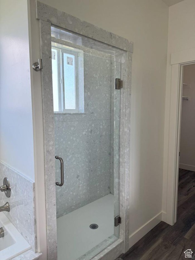 full bathroom with a shower stall, wood finished floors, baseboards, and a garden tub