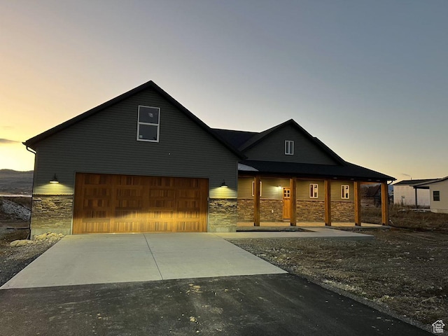 view of front facade with a garage, stone siding, and aphalt driveway