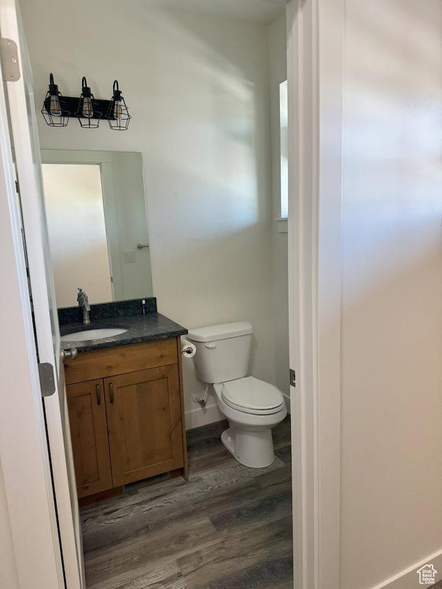 bathroom featuring toilet, vanity, wood finished floors, and baseboards