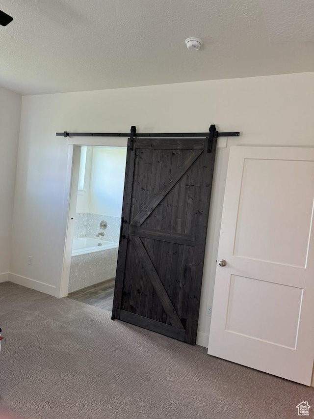 carpeted bedroom featuring a textured ceiling and a barn door