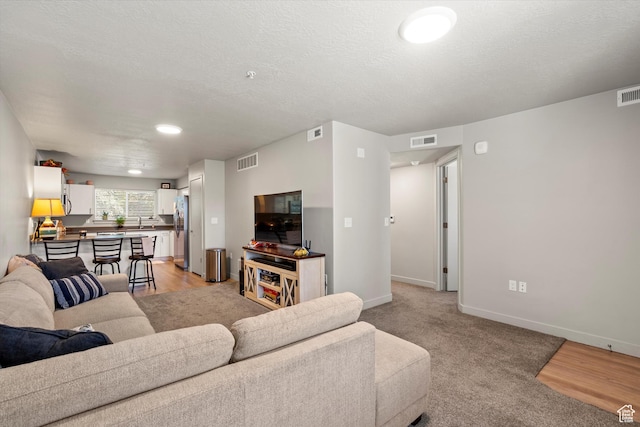 living room featuring baseboards, visible vents, and a textured ceiling