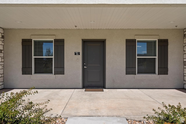 view of exterior entry featuring a patio area and stucco siding