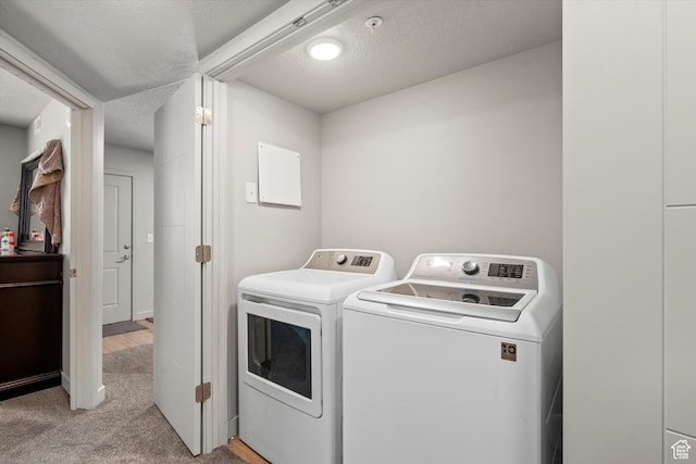 laundry area with laundry area, a textured ceiling, light colored carpet, and independent washer and dryer