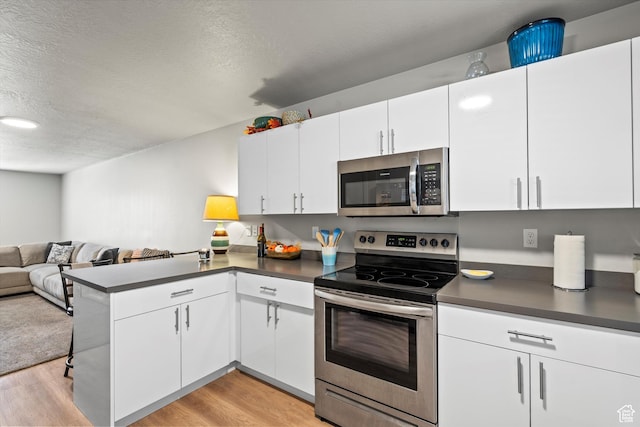 kitchen featuring dark countertops, appliances with stainless steel finishes, and light wood-style flooring
