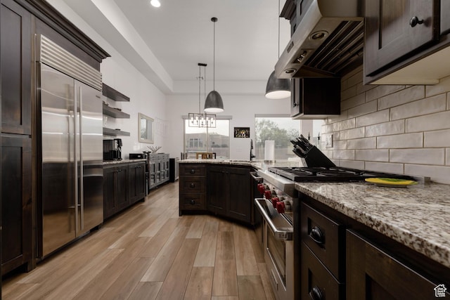 3318 S Red Rock Way, Hurricane, UT 84737 - kitchen with high quality appliances, tasteful backsplash, light wood-style flooring, under cabinet range hood, and dark brown cabinets