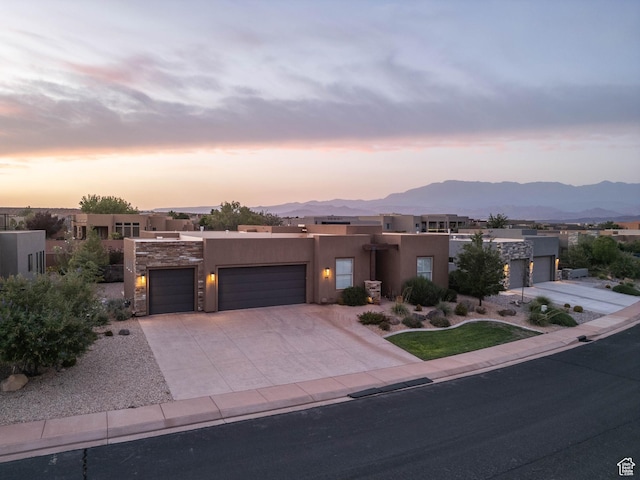3318 S Red Rock Way, Hurricane, UT 84737 - pueblo revival-style home with stucco siding, an attached garage, a mountain view, and concrete driveway
