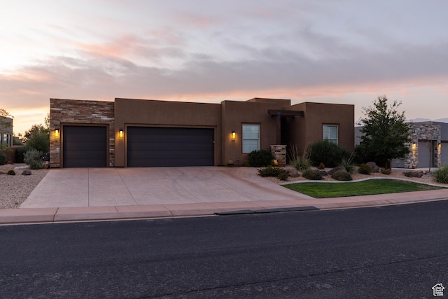 3318 S Red Rock Way, Hurricane, UT 84737 - pueblo revival-style home with driveway, an attached garage, stone siding, and stucco siding