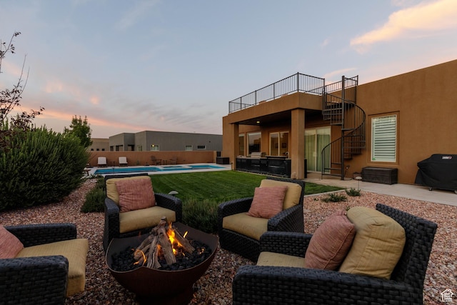 3318 S Red Rock Way, Hurricane, UT 84737 - patio terrace at dusk featuring grilling area, a fire pit, stairs, and a fenced in pool