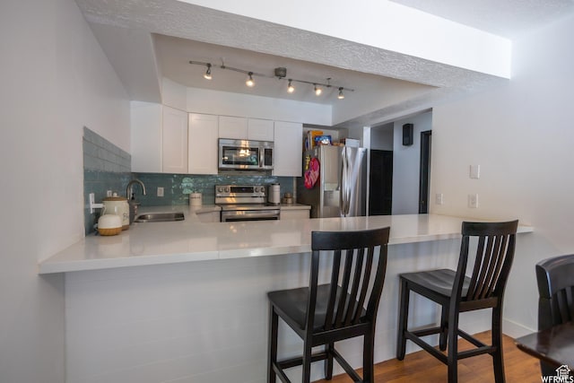 4424 W Skye Dr, South Jordan, UT 84009 - kitchen with a sink, appliances with stainless steel finishes, a peninsula, wood finished floors, and decorative backsplash