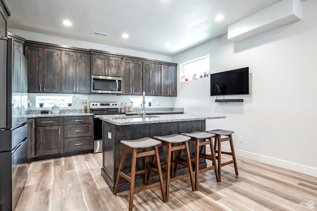 668 S 400 E, Clearfield, UT 84015 - kitchen featuring stainless steel appliances, dark brown cabinets, light wood-style flooring, a kitchen breakfast bar, and recessed lighting
