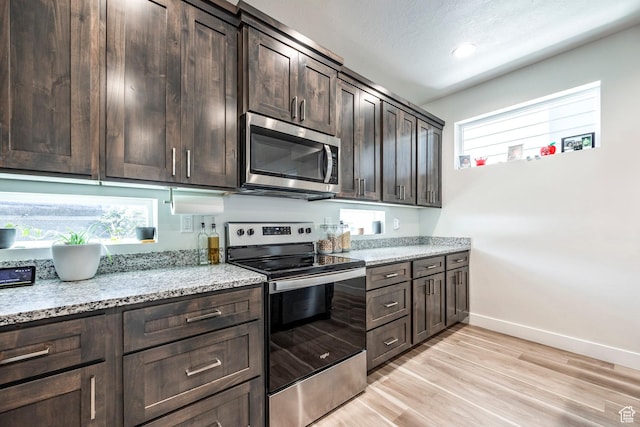 668 S 400 E, Clearfield, UT 84015 - kitchen featuring stainless steel appliances, dark brown cabinetry, baseboards, light wood finished floors, and light stone counters