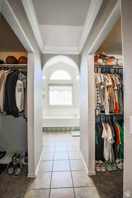 hallway featuring crown molding, arched walkways, and tile patterned floors