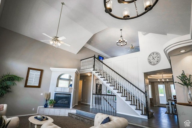 living area featuring stairs, high vaulted ceiling, wood finished floors, and a fireplace