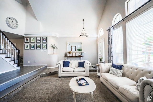 living area with stairs, wood finished floors, baseboards, high vaulted ceiling, and a notable chandelier