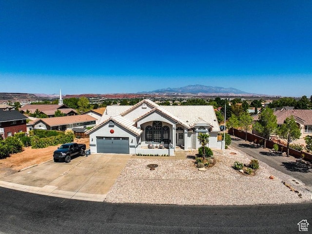 view of front of house featuring a garage, stucco siding, a tiled roof, a mountain view, and driveway