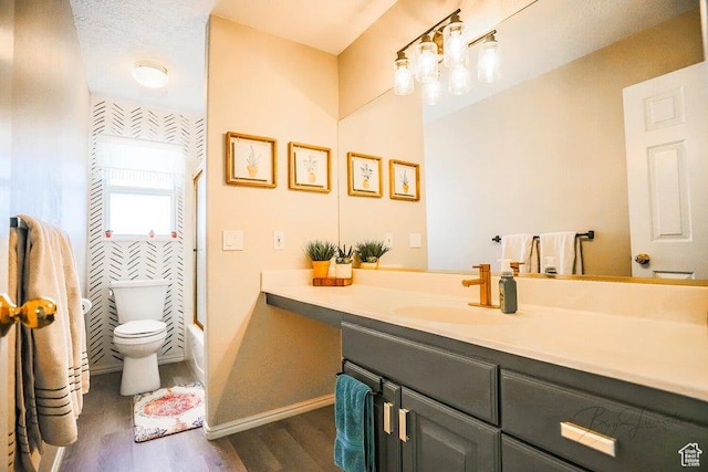 bathroom with washtub / shower combination, vanity, toilet, baseboards, and wood finished floors