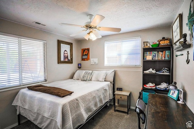 carpeted bedroom featuring visible vents, a textured ceiling, ceiling fan, and baseboards