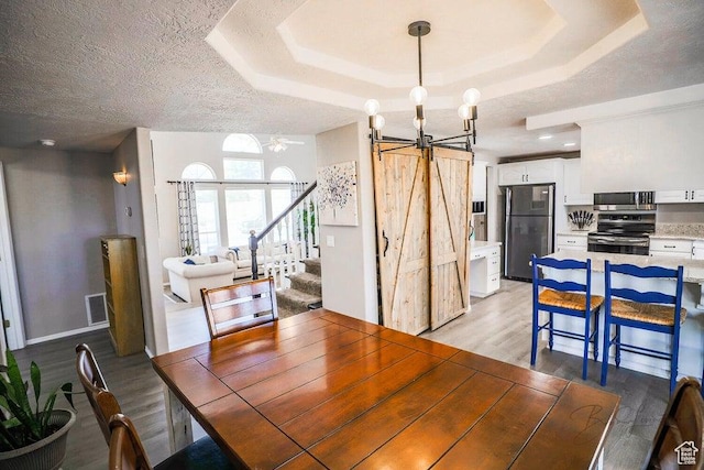 dining room featuring light wood-style floors, stairway, a tray ceiling, and a chandelier