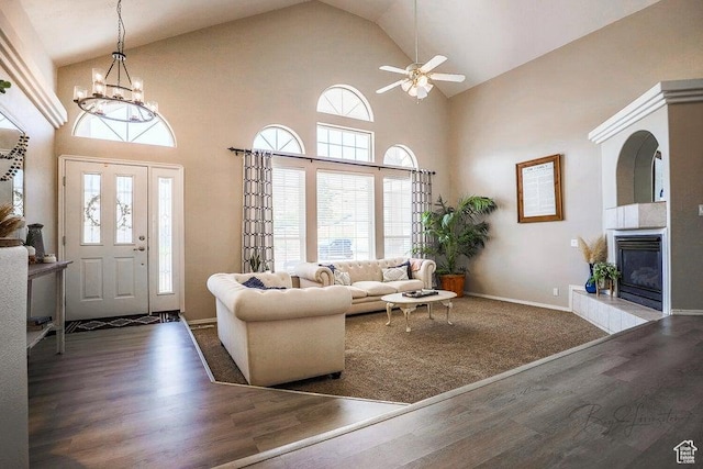 living area with a fireplace, high vaulted ceiling, a healthy amount of sunlight, and wood finished floors