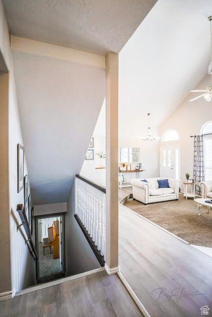 stairway with a ceiling fan, wood finished floors, and lofted ceiling
