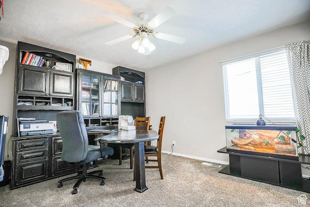 carpeted office space featuring a ceiling fan, baseboards, and visible vents