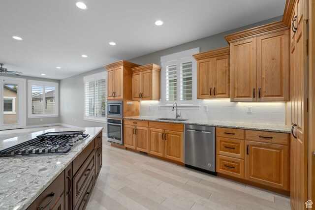 kitchen featuring light stone counters, a sink, backsplash, appliances with stainless steel finishes, and recessed lighting