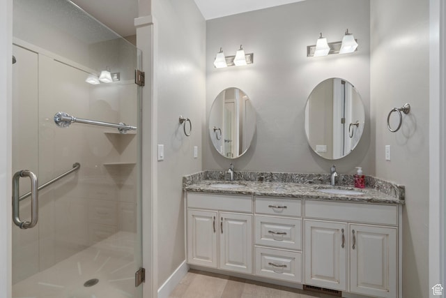 bathroom featuring double vanity, a sink, a shower stall, and visible vents