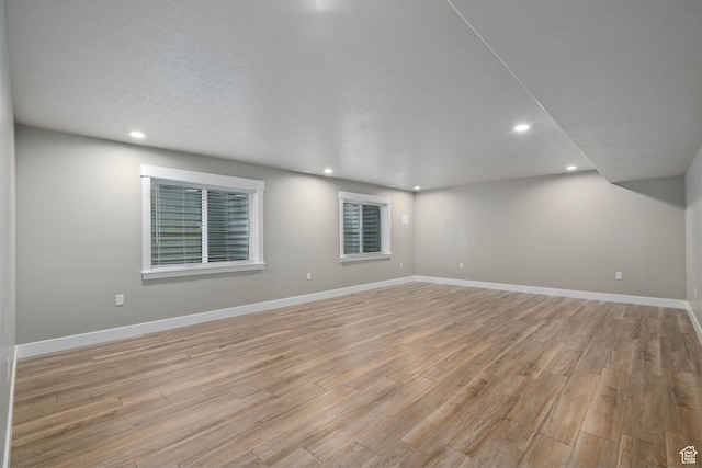 spare room with baseboards, a textured ceiling, recessed lighting, and light wood-style floors
