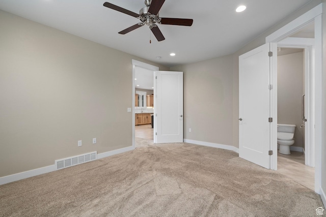 unfurnished bedroom with baseboards, connected bathroom, visible vents, and light carpet