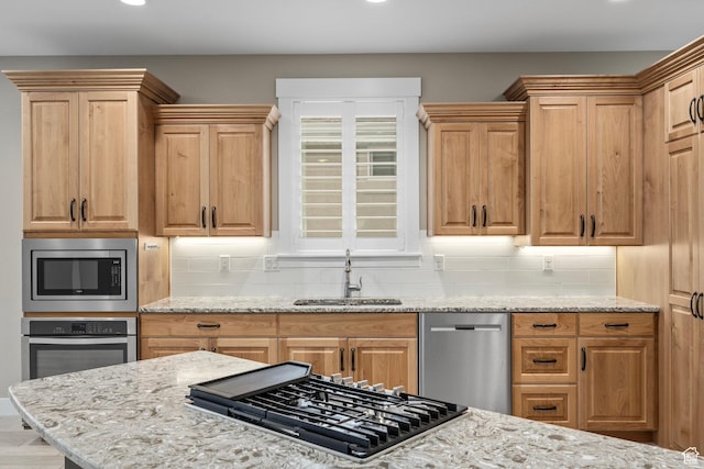 kitchen with decorative backsplash, light stone countertops, a sink, and stainless steel appliances