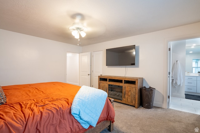 bedroom featuring light carpet, ceiling fan, and ensuite bathroom