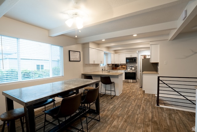 dining space with beamed ceiling, sink, dark wood-type flooring, and ceiling fan
