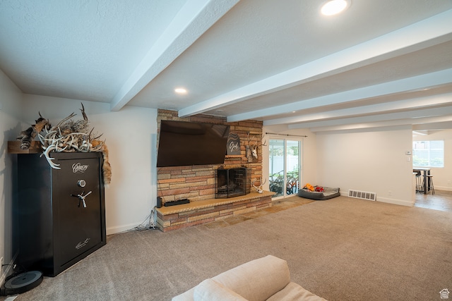 carpeted living room featuring a stone fireplace, beamed ceiling, plenty of natural light, and a textured ceiling