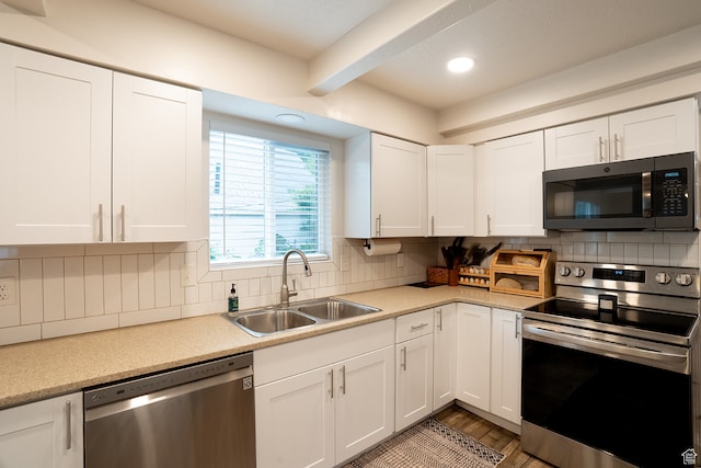 kitchen with sink, tasteful backsplash, light hardwood / wood-style flooring, white cabinetry, and stainless steel appliances
