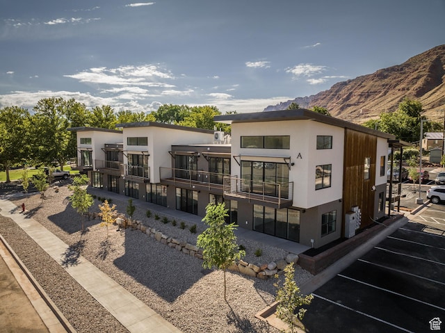 443 W Kane Creek Blvd Unit A204, Moab, UT 84532 - rear view of property featuring a balcony, uncovered parking, a mountain view, and stucco siding