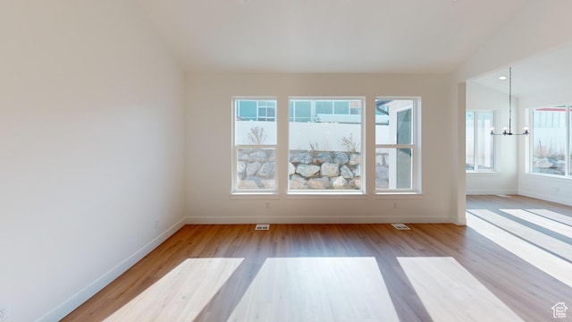 spare room featuring vaulted ceiling, baseboards, visible vents, and wood finished floors