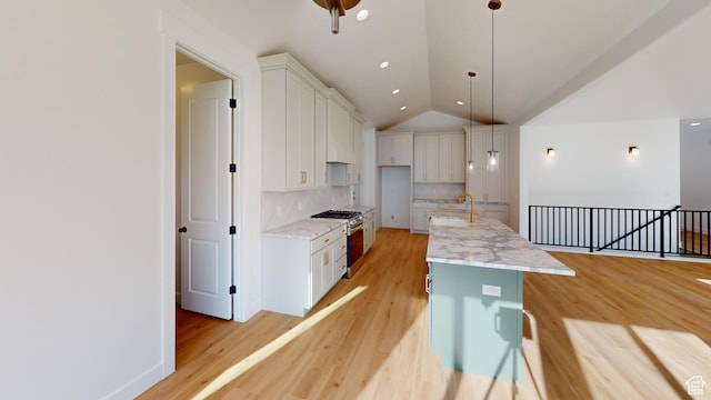 kitchen with gas stove, light wood-style floors, and a sink