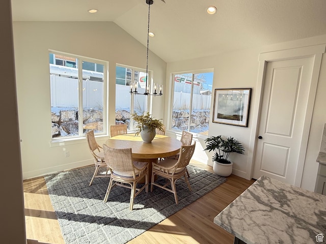 dining room featuring a wealth of natural light, a notable chandelier, dark wood finished floors, and vaulted ceiling