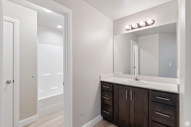 full bathroom featuring baseboards, vanity, wood finished floors, and bathtub / shower combination