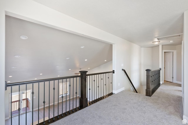 hall with an upstairs landing, carpet floors, and baseboards