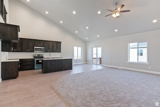 kitchen with stainless steel appliances, open floor plan, high vaulted ceiling, plenty of natural light, and recessed lighting