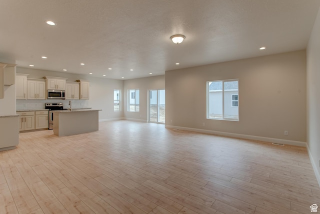 1641 S Windsong Dr Unit 371, Santaquin, UT 84655 - unfurnished living room featuring a sink, baseboards, light wood-style flooring, and recessed lighting