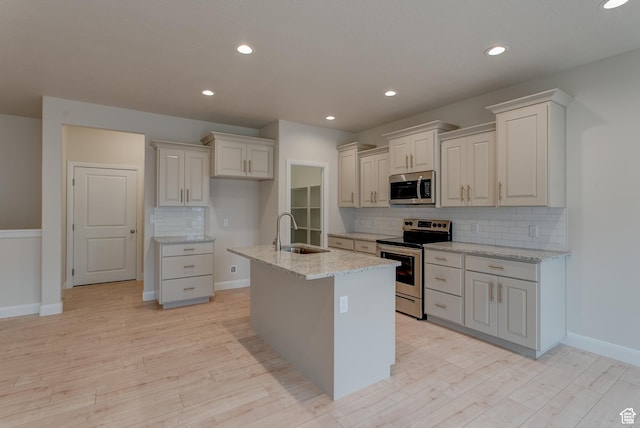 1641 S Windsong Dr Unit 371, Santaquin, UT 84655 - kitchen with stainless steel appliances, a sink, decorative backsplash, light wood finished floors, and light stone counters