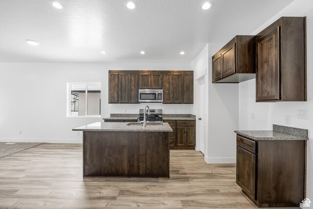 1701 S Windsong Dr Unit 377, Santaquin, UT 84655 - kitchen with appliances with stainless steel finishes, light wood-type flooring, dark brown cabinets, a kitchen island with sink, and sink