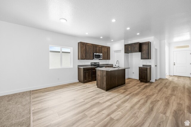 1701 S Windsong Dr Unit 377, Santaquin, UT 84655 - kitchen with dark brown cabinetry, a textured ceiling, a kitchen island with sink, appliances with stainless steel finishes, and light hardwood / wood-style floors