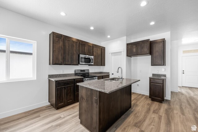 1701 S Windsong Dr Unit 377, Santaquin, UT 84655 - kitchen with light hardwood / wood-style floors, a textured ceiling, a kitchen island with sink, sink, and stainless steel appliances