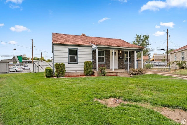 37 N Lakeview Dr, Clearfield, UT 84015 - view of front of home featuring a front yard, covered porch, stone siding, fence, and a tiled roof
