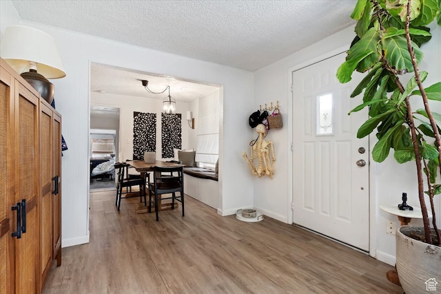 foyer entrance with a textured ceiling, a chandelier, and hardwood / wood-style flooring