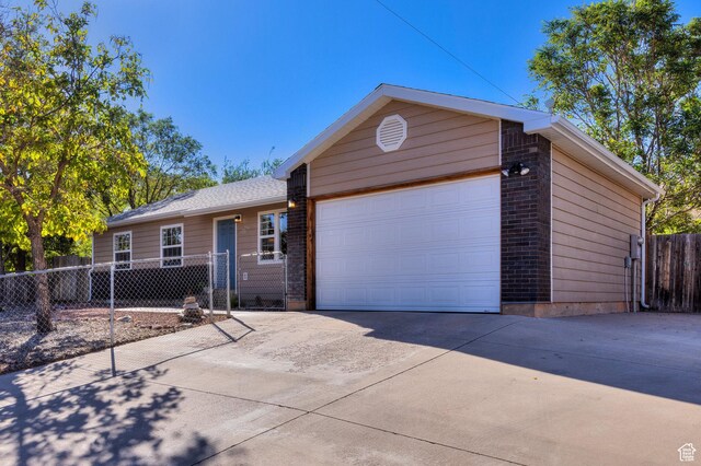 1122 E Holyoak Ln, Moab, UT 84532 - ranch-style house with brick siding, a garage, fence, and concrete driveway