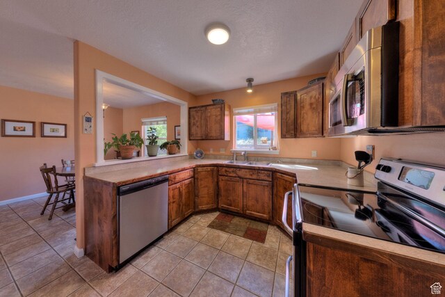 1122 E Holyoak Ln, Moab, UT 84532 - kitchen with brown cabinetry, light tile patterned flooring, light countertops, a sink, and appliances with stainless steel finishes